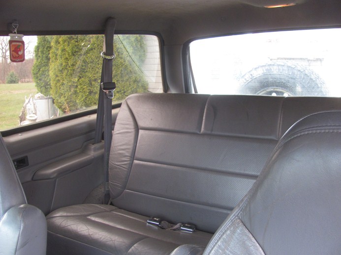 1996 Ford Bronco interior showing rear leather seats and spare tire visible through rear window
