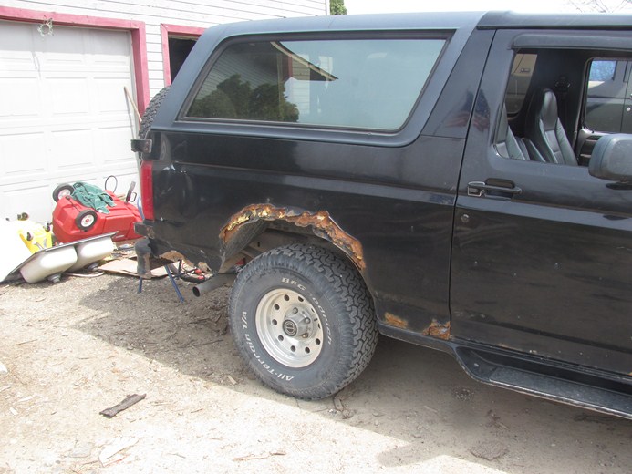 1996 Ford Bronco side view showing rust damage on the rear wheel well and rocker panel