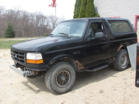 1996 Ford Bronco - This black Ford Bronco shows significant rust damage on its body panels.