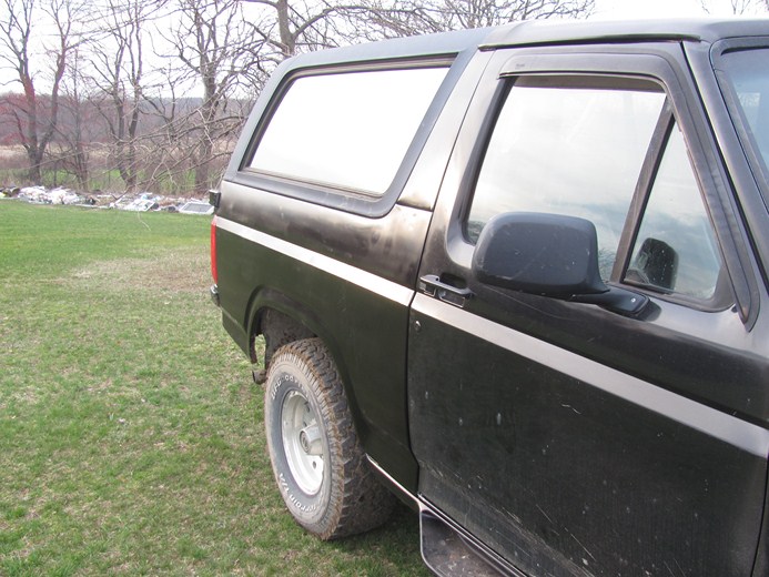 1996 Ford Bronco side view, parked on grass with trees in background