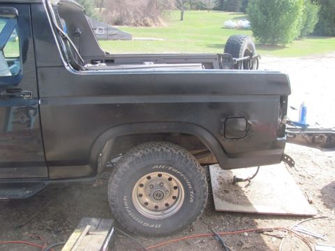 1996 Ford Bronco - This black Ford Bronco is shown from the side, with its rear quarter panel and spare tire visible.