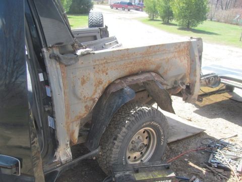 1996 Ford Bronco - This is a heavily rusted truck bed and fender section, showing a tire and wheel.