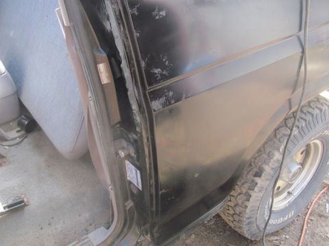 1996 Ford Bronco - Close-up view of the interior and exterior of a black Ford Bronco, focusing on the door frame and rear wheel.