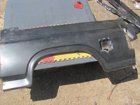 1996 Ford Bronco - This is a rear fender part, likely from a truck or SUV, with a visible fuel door opening. The part is black and sits on a gray surface.