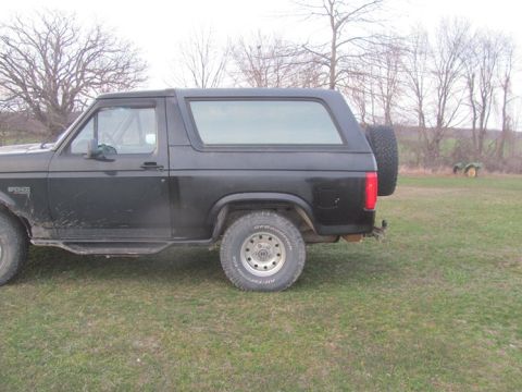 1996 Ford Bronco - Side profile of a black 1996 Ford Bronco SUV, a spare tire mounted on the back.