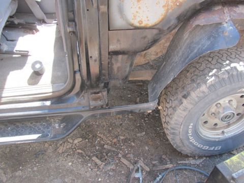 1996 Ford Bronco - This image shows the interior door frame and a tire of a vehicle, with visible rust on the exterior body panels.