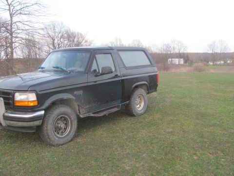 1996 Ford Bronco - This black 1996 Ford Bronco is shown from a three-quarter front view in an open field.