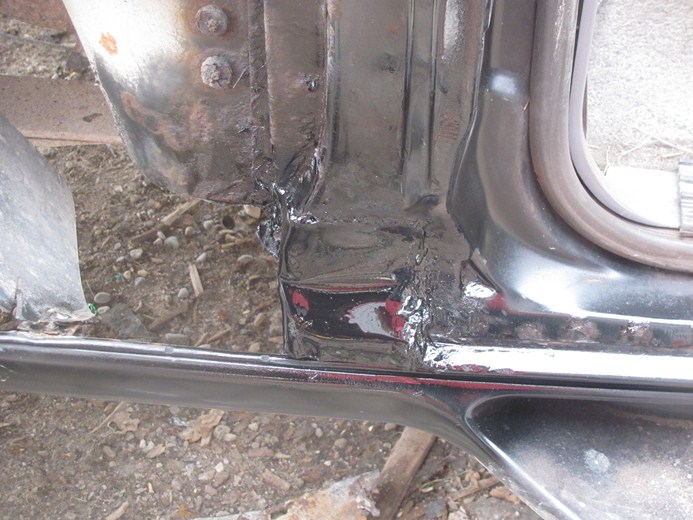 Close-up of rusty metal and black paint on a vehicle's lower body panel