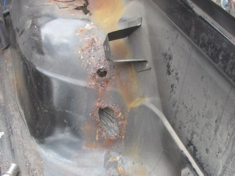 1996 Ford Bronco - This close-up shows significant rust damage and a metal bracket on the floor pan of a vehicle.
