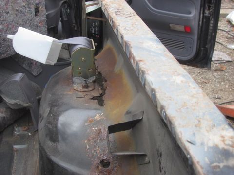 1996 Ford Bronco - The interior of a vehicle displays significant rust on its metal components and a visible seatbelt assembly.