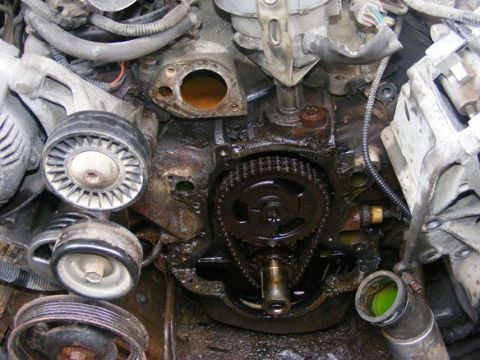 1996 Ford Bronco - Close-up view of an engine's timing chain and gears, with a visible leak of green coolant.