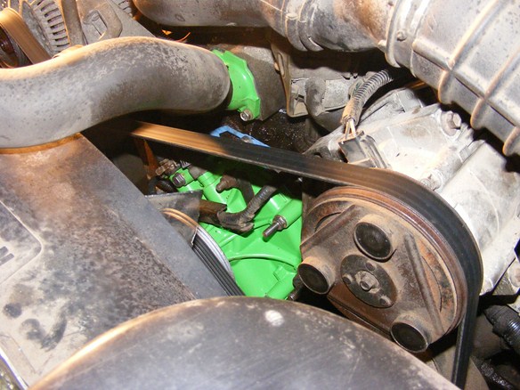 Engine bay with green painted component, serpentine belt, and pulley