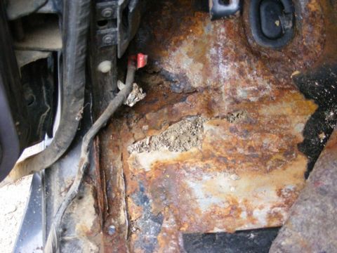 1996 Ford Bronco - Severe rust damage is visible on the vehicle's floor pan, with exposed wiring.