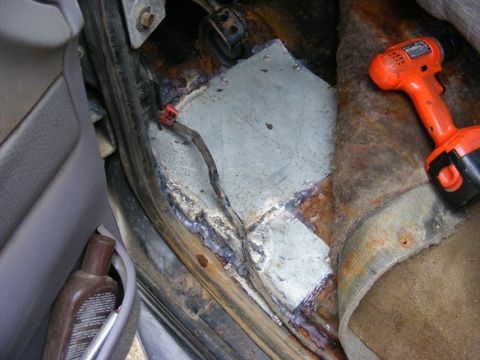 1996 Ford Bronco - This photo shows the interior floor of a vehicle undergoing rust repair with a welded metal patch and a cordless drill nearby.