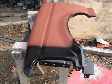 1996 Ford Bronco - A car fender, partially painted, rests on sawhorses in an outdoor setting.