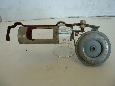 1994 Ford Bronco - A close-up view of a rusted metal assembly, a glass cylinder and a round metal component with 'Delco' visible.