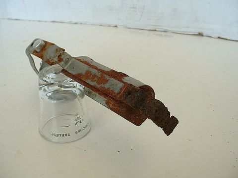 1994 Ford Bronco - A heavily rusted metal component is placed on a glass measuring cup.