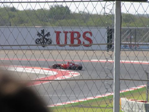 2006 BMW 5 Series - A Formula 1 race car navigates a turn at the Circuit of the Americas, with a large UBS advertisement visible.