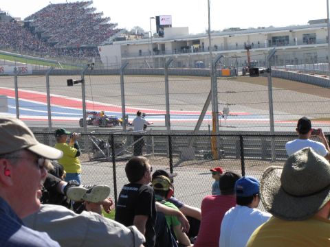 2006 BMW 5 Series - A race car speeds around a track, observed by a crowd in the stands.
