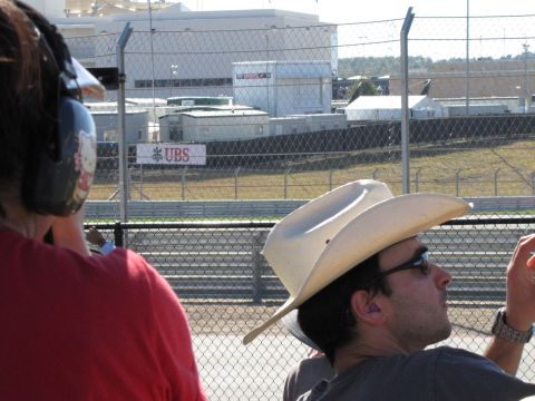 2006 BMW 5 Series - Spectators at a race track observe the event, with a UBS advertisement visible in the distance.