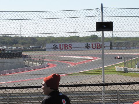 2006 BMW 5 Series - A race car navigates a turn at a circuit with sponsor advertisements visible.