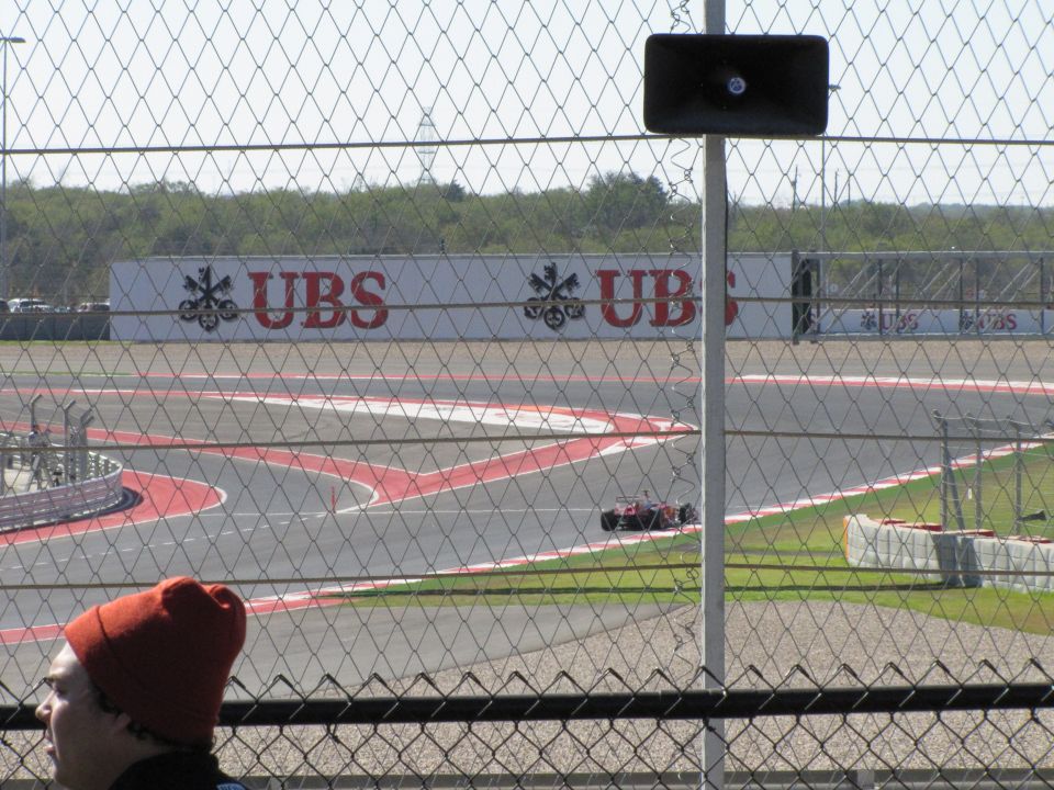 Red race car on track with UBS advertisement in background