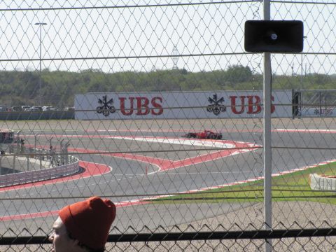 2006 BMW 5 Series - A red race car navigates a turn on a circuit, with UBS branding visible on a wall.