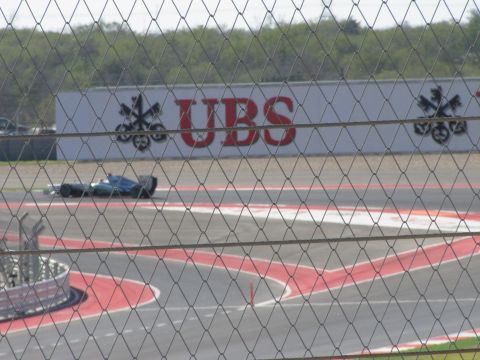 2006 BMW 5 Series - A race car speeds around a track, with a large UBS advertisement visible on a wall behind it.