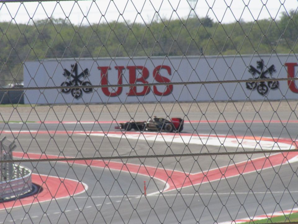 Race car with red rear wing on track, UBS advertisement in background