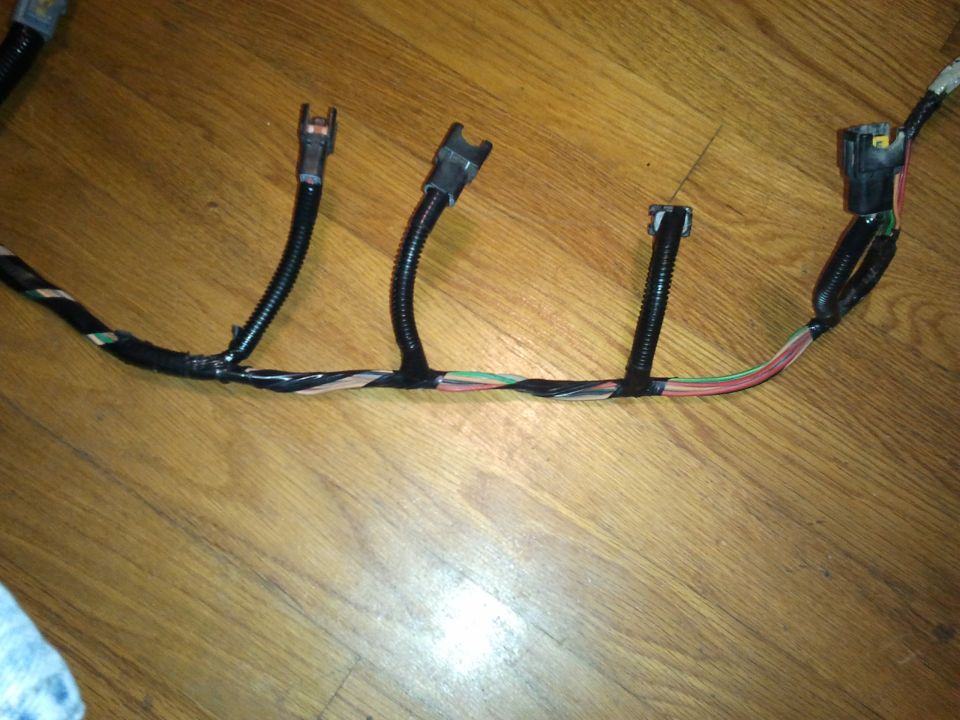 Automotive wiring harness with multiple connectors and colored wires on a wooden surface