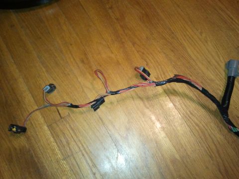 1990 Ford Bronco - A wiring harness with several connectors and red and black wires is shown on a wooden surface.