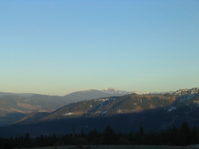 Mountain landscape under a clear blue sky with a shadow cast across the hills
