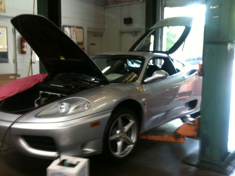 1990 Ford Bronco - A silver Ferrari 360 Modena is shown with its hood and doors open while elevated on a service lift.
