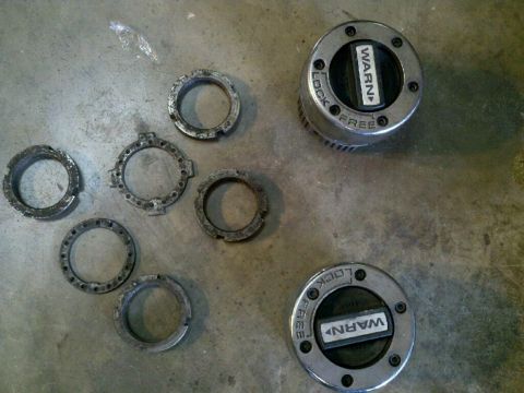 1995 Ford Bronco - Warn manual locking hubs and rings are laid out on a concrete surface.