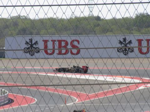 2006 BMW 5 Series - A Formula 1 race car is seen on the track at the Circuit of the Americas, with a large UBS advertisement in the background.
