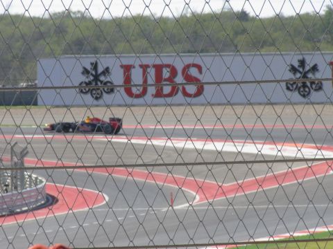 2006 BMW 5 Series - A Formula 1 car races on a track, with a large UBS advertisement visible behind it.