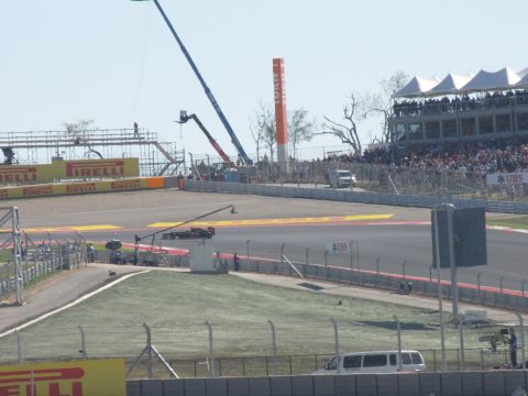 2006 BMW 5 Series - A race track scene with spectators in the grandstands and various vehicles present.