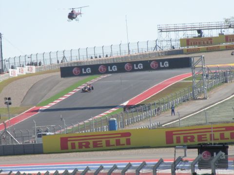 2006 BMW 5 Series - A race car competes on a track with a helicopter overhead and sponsor banners displayed.