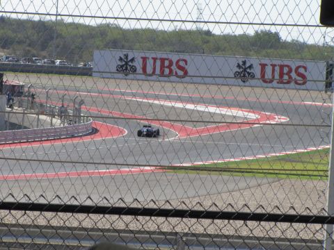 2006 BMW 5 Series - A race car navigates a turn on a circuit, with sponsor banners visible in the distance.
