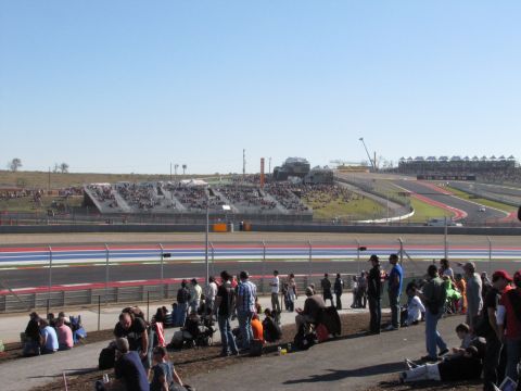 2006 BMW 5 Series - Spectators gather at a race track, with grandstands visible in the background.