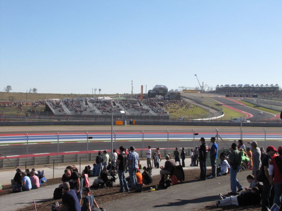 Race track with grandstands full of spectators under a clear blue sky