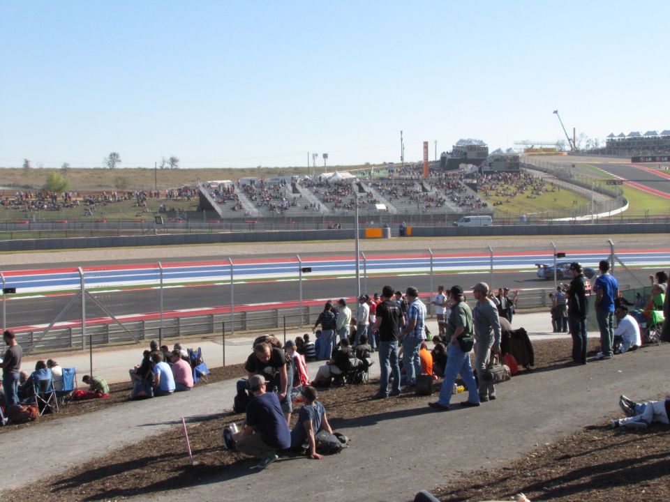 People watching a race at a track with grandstands in the background