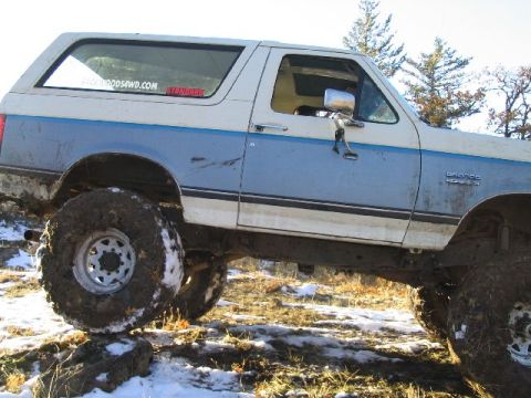 1988 Ford Bronco - This 1988 Ford Bronco is equipped for off-road use, navigating a challenging terrain with snow and rocks.