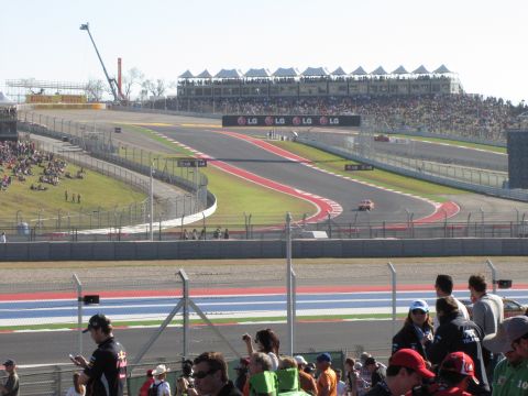 2006 BMW 5 Series - A race is underway at the Circuit of the Americas, with spectators filling the grandstands and cars visible on the track.