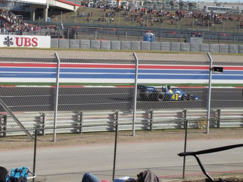 2006 BMW 5 Series - A race car speeds around a track with spectators in the background.