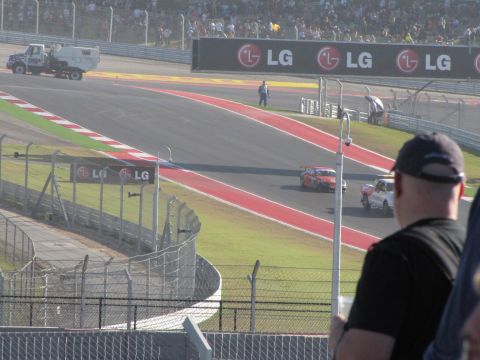 2006 BMW 5 Series - A race is underway on a track with multiple cars and spectators watching from the stands.