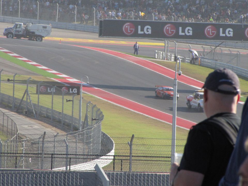 Race cars on a track with spectators in the background and LG billboards