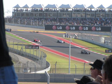 2006 BMW 5 Series - Multiple race cars compete on a track with grandstands full of spectators and LG advertisements.