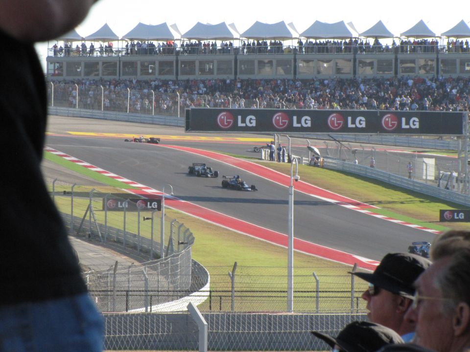 Formula 1 race cars on a track with LG billboards and spectators