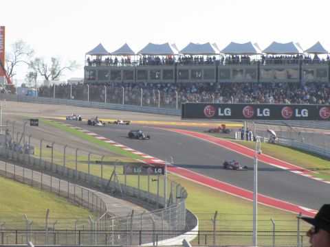 2006 BMW 5 Series - Formula 1 race cars compete on a track with grandstands filled with spectators.